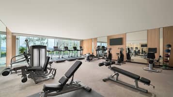 Una sala de gimnàstica moderna amb diversos equips d'exercici, grans finestres i un mirall.