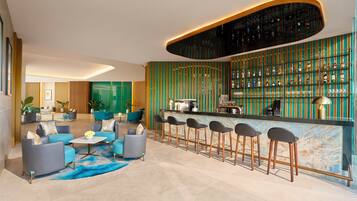 A modern bar area with a curved ceiling, a bar counter, and a seating area with sofas and bar stools.