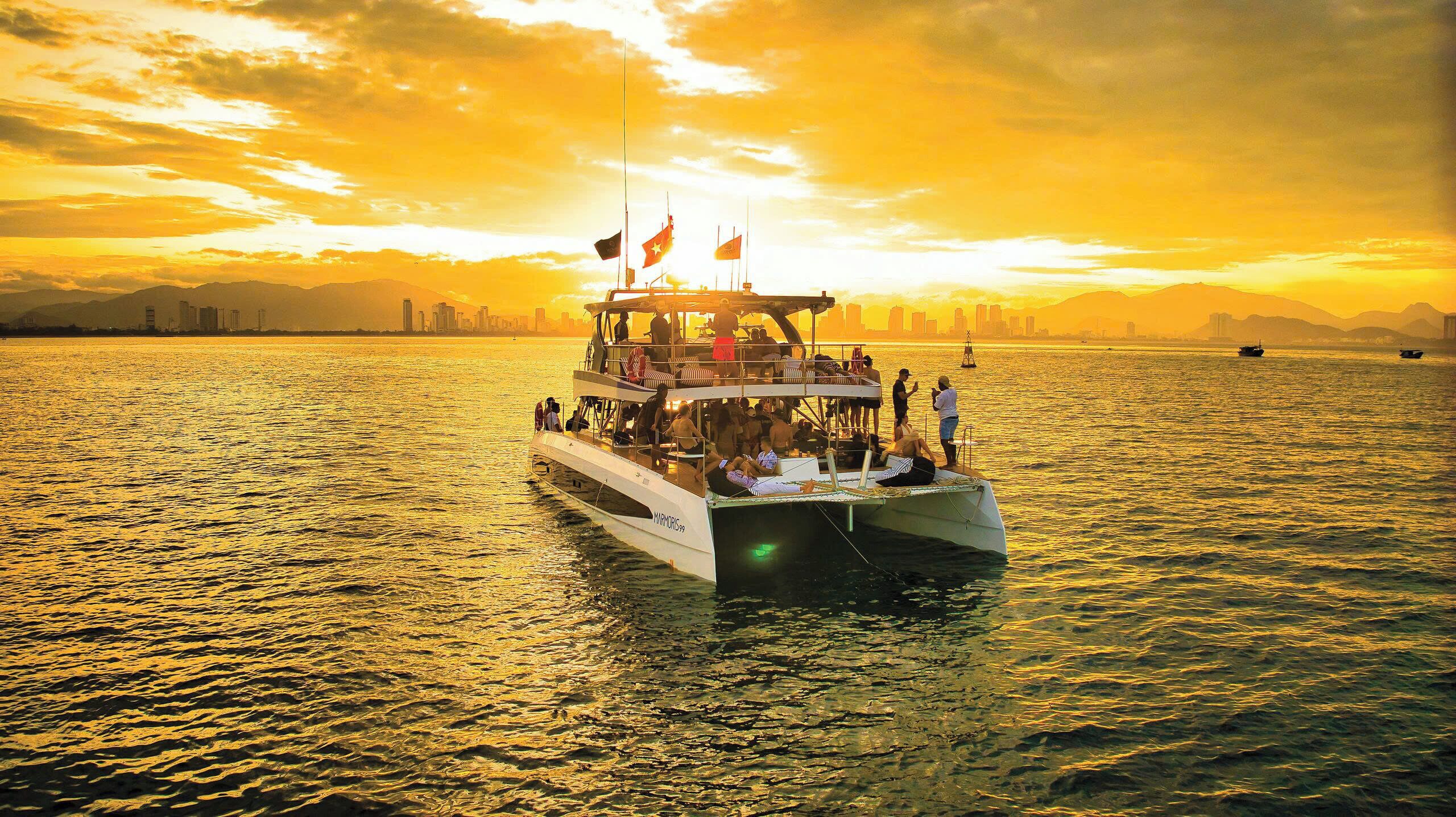 A boat with multiple decks and passengers, docked at a harbor with a city skyline in the background.