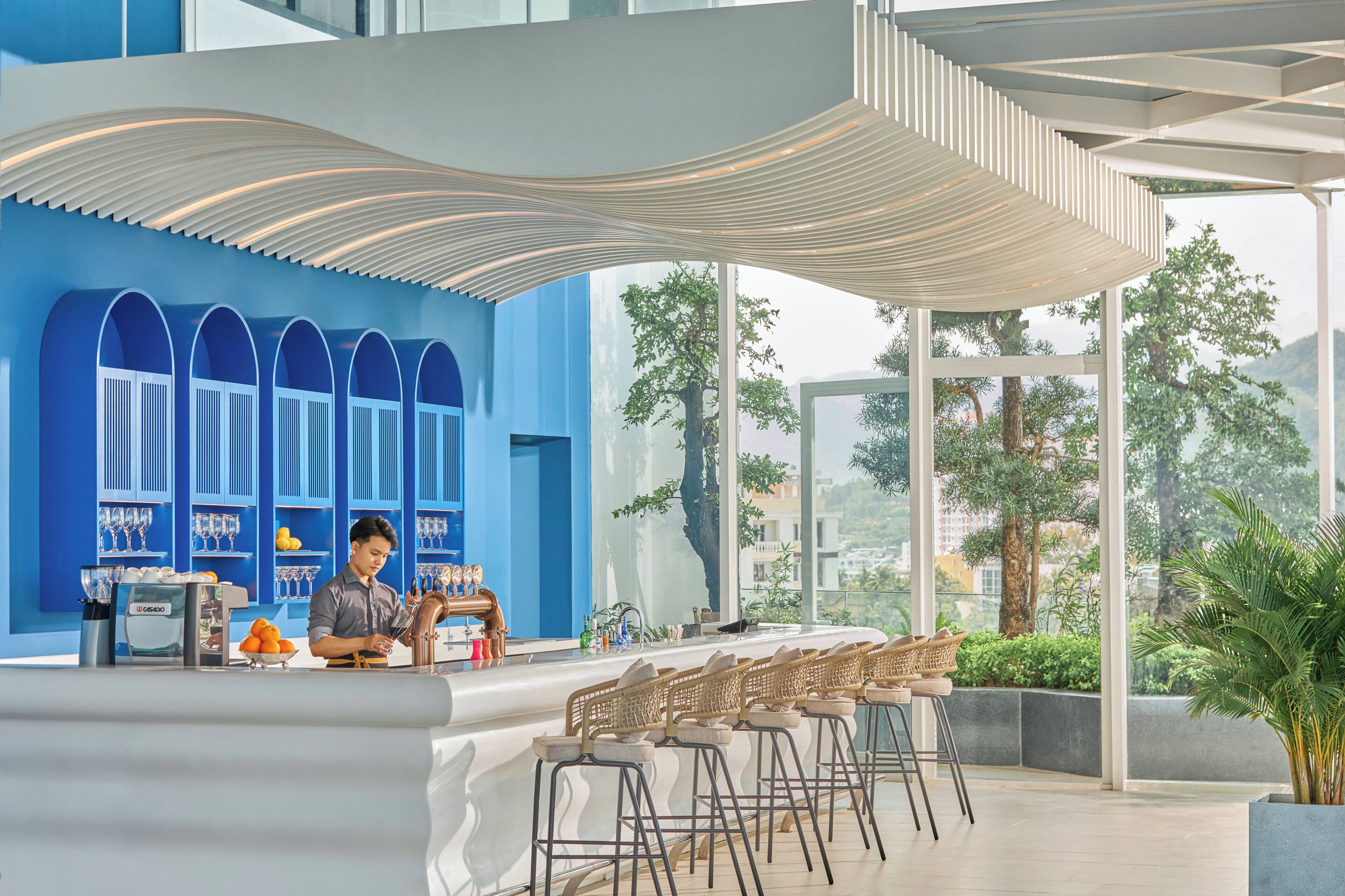 A modern bar area with a blue wall, bar stools, and a coffee machine.