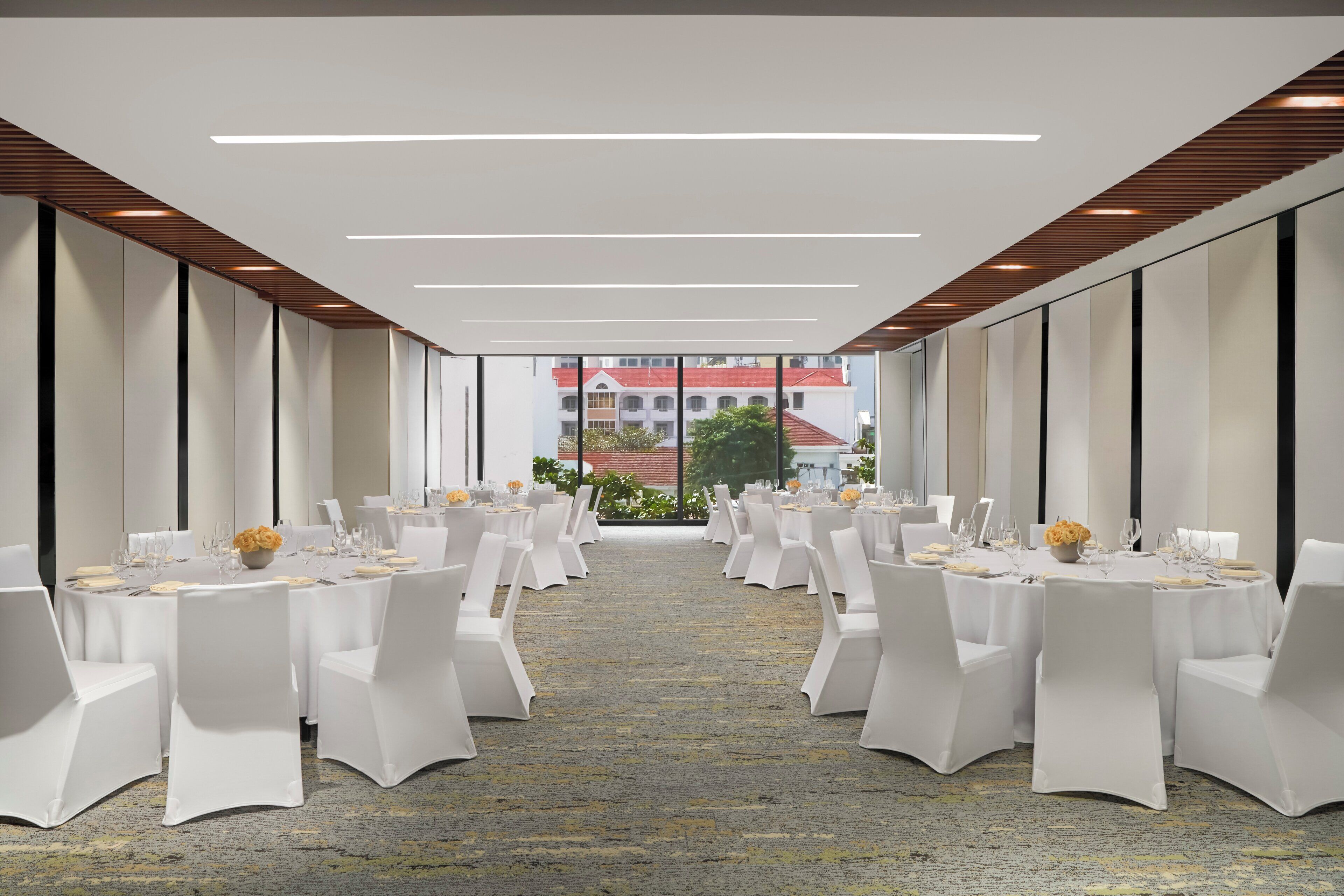 A conference room with round tables, white chairs, and a carpeted floor.