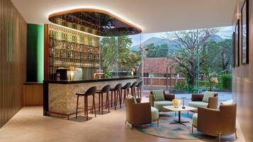A bar area with a curved counter, multiple stools, and a seating area with sofas and a coffee table.