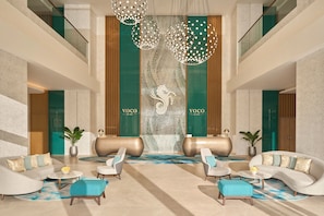 Un vestíbulo moderno con mostrador de recepción, zona de estar e iluminación decorativa.