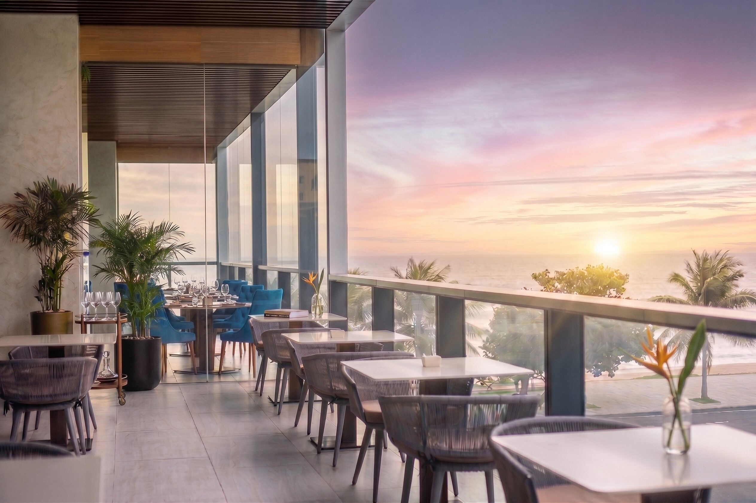Un espace extérieur aménagé pour les repas, avec des tables et des chaises, offrant une vue panoramique sur un magnifique coucher de soleil.