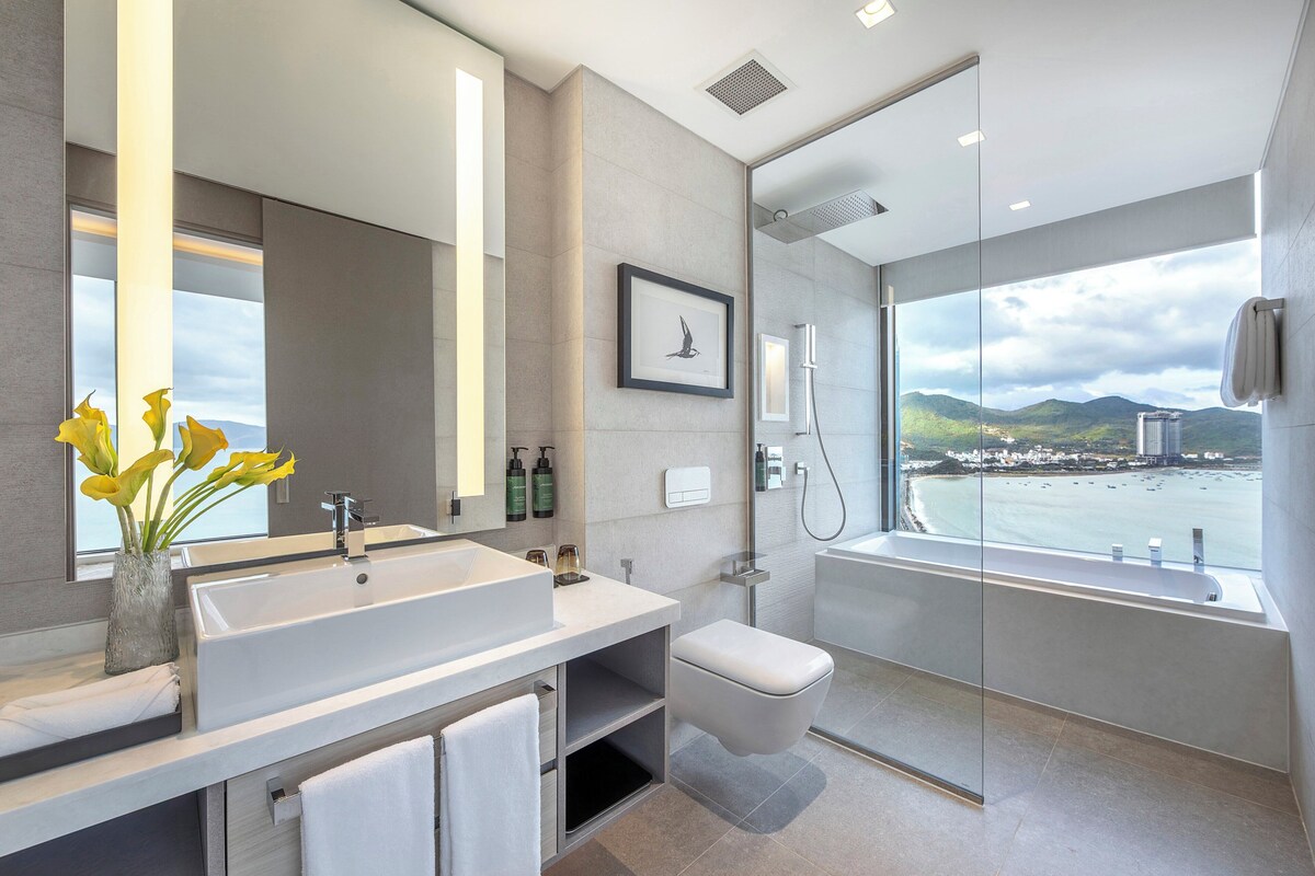A modern bathroom with a large sink, toilet, and glass-enclosed shower.