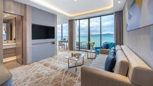 Una sala de estar moderna con un televisor grande, un sofá, una mesa de centro y vistas al mar.