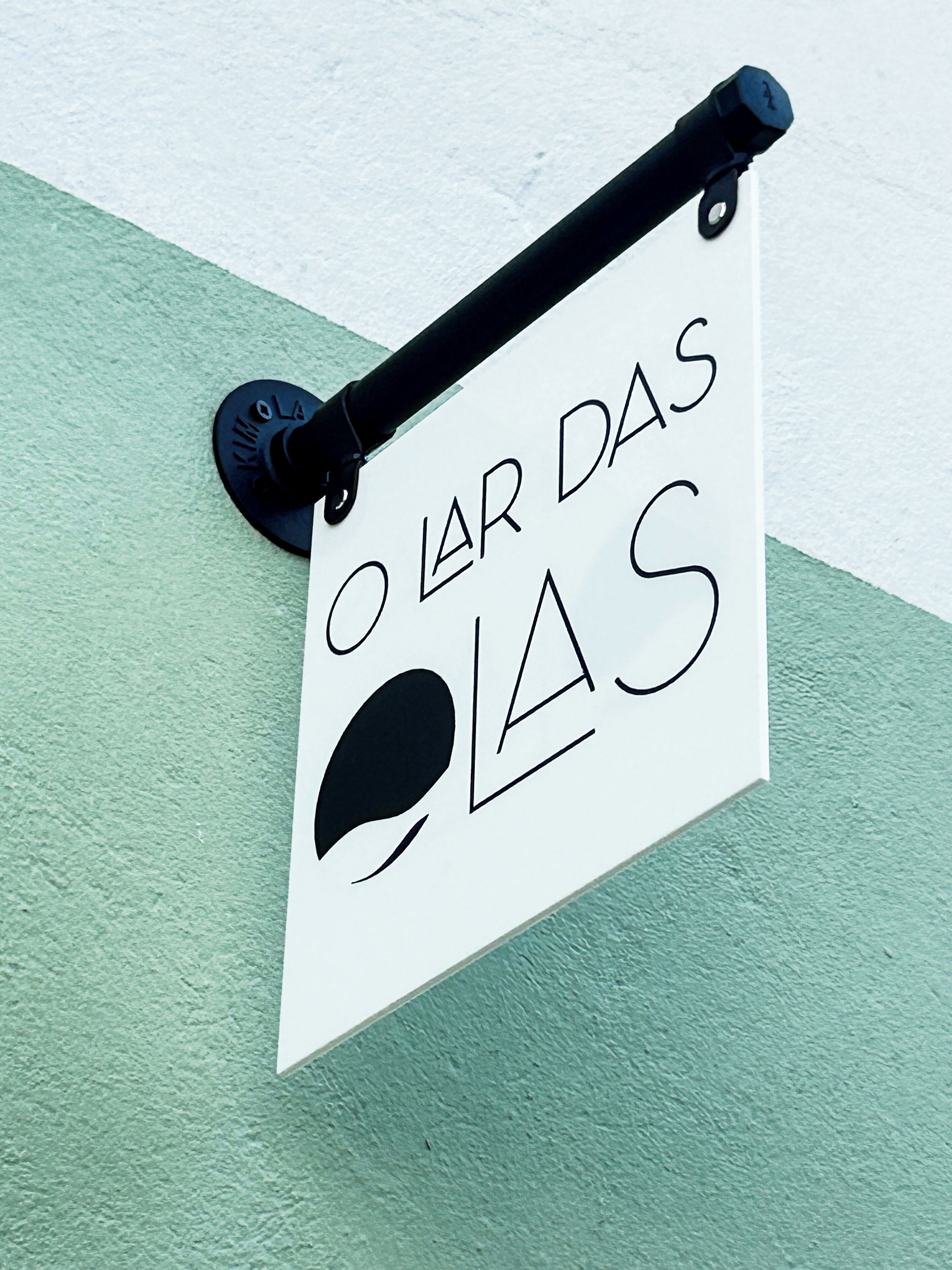 A sign with a black handle and a white background, featuring stylized text and a black circle.