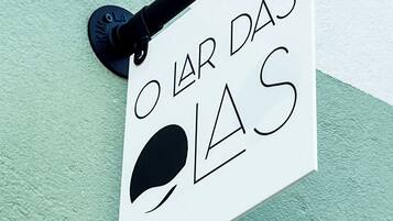 A sign with a black handle and a white background, featuring stylized text and a black circle.