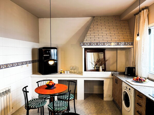 A compact kitchen with a dining area, a coffee machine, and a washing machine.