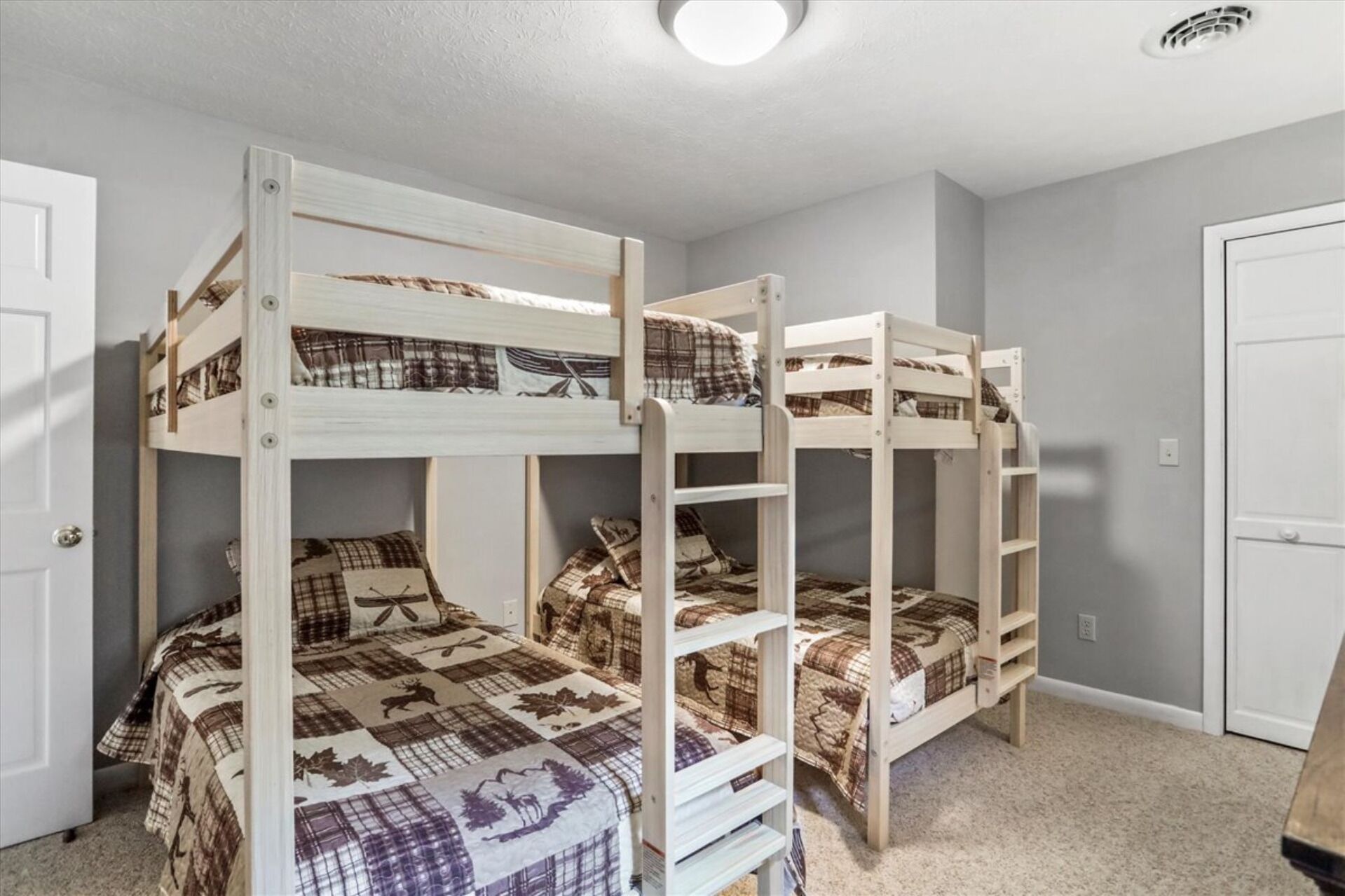 Ein Zimmer mit drei Etagenbetten, jeweils mit einer karierten Bettdecke.