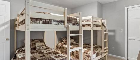 Ein Zimmer mit drei Etagenbetten, jeweils mit einer karierten Bettdecke.
