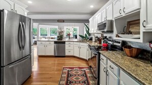 A modern kitchen with white cabinets, stainless steel appliances, and a granite countertop. - Deep Forest Dream- Aunt Susies Raystown Lake (James Creek)