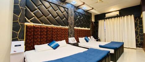 A hotel room with two beds, a modern design with geometric wall patterns, a ceiling fan, and a large window with curtains.
