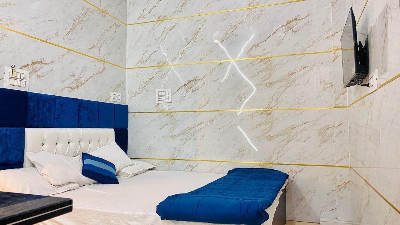 A modern bedroom with a marble wall, a blue headboard, and a bed with white and blue bedding.