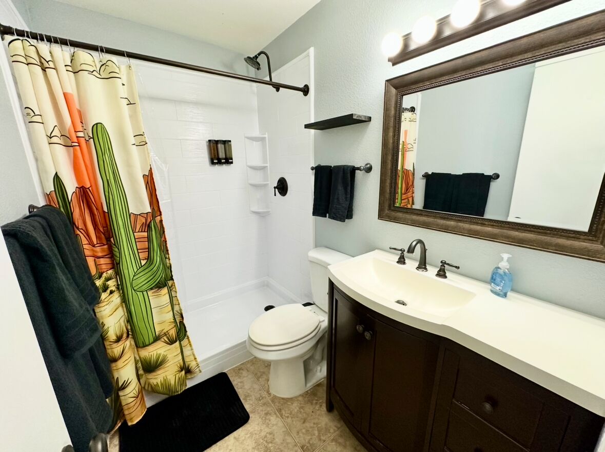 Ein Badezimmer mit Duschvorhang, Toilette, Waschbecken und Spiegel.