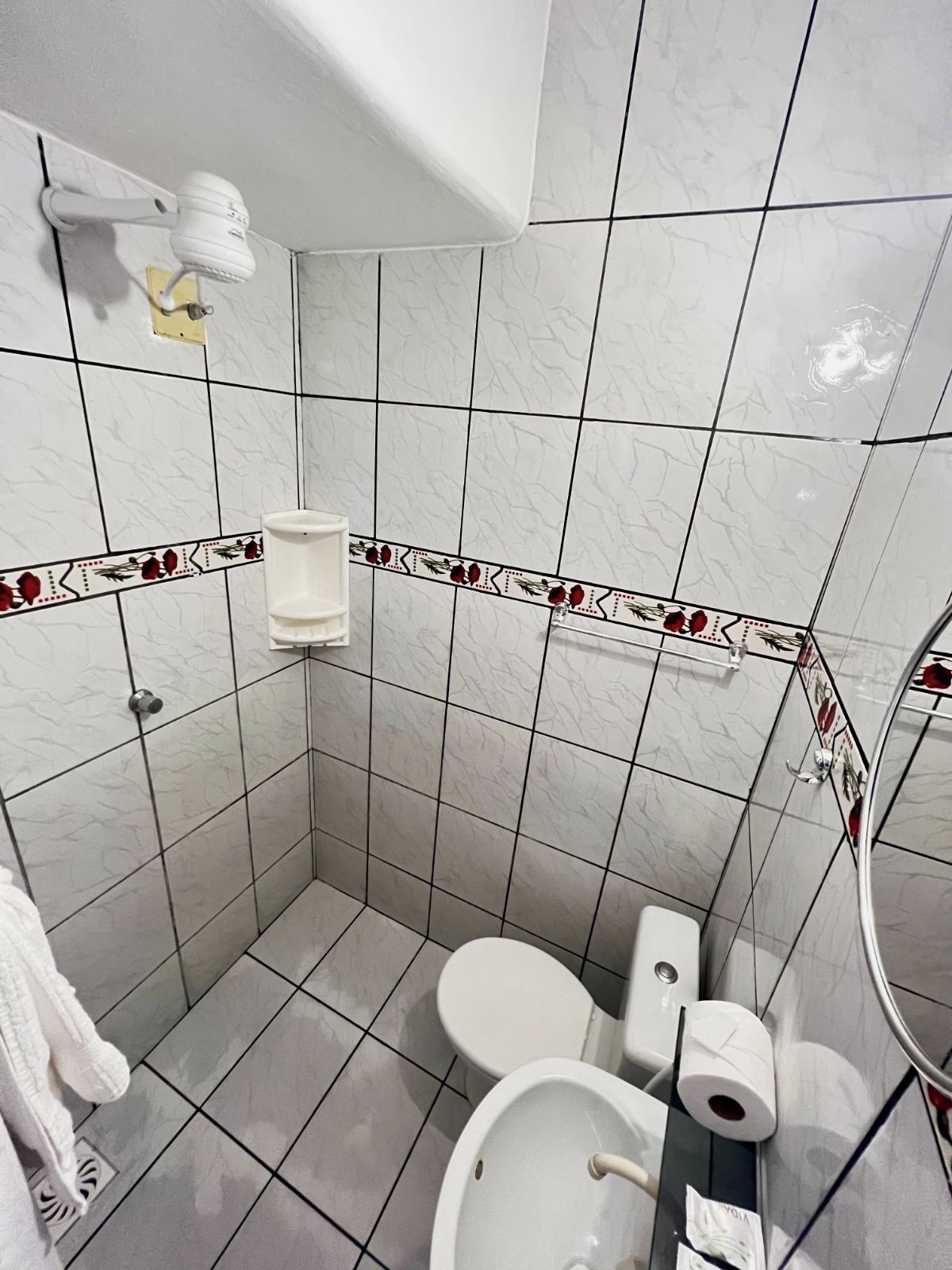 A bathroom with a toilet, a sink, a towel rack, and a shower.