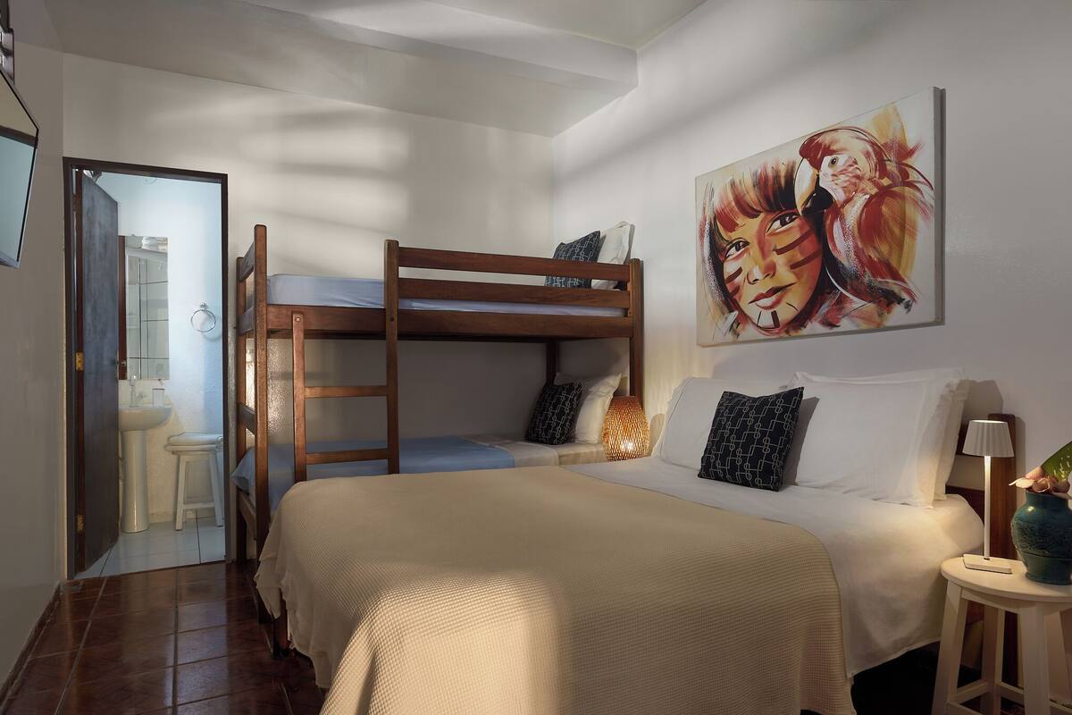 Dormitorio con literas, un cuadro, una lámpara de noche y una mesita.