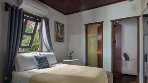A bedroom with a bed, a window with curtains, a small table with a vase, and a painting on the wall. - Pousada Casa Cecilia (Jijoca de Jericoacoara)