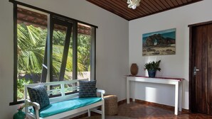 A room with a white bench, a small table with a potted plant, and a painting on the wall. - Pousada Casa Cecilia (Jijoca de Jericoacoara)