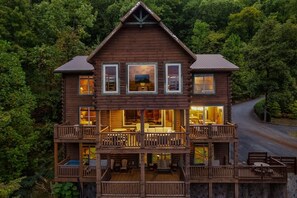 A two-story log cabin with a balcony, large windows, and a dining area.