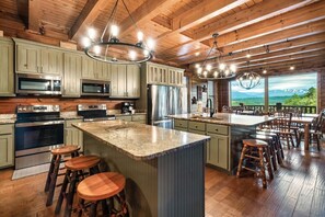 A kitchen with granite countertops, stainless steel appliances, and a large island with stools.