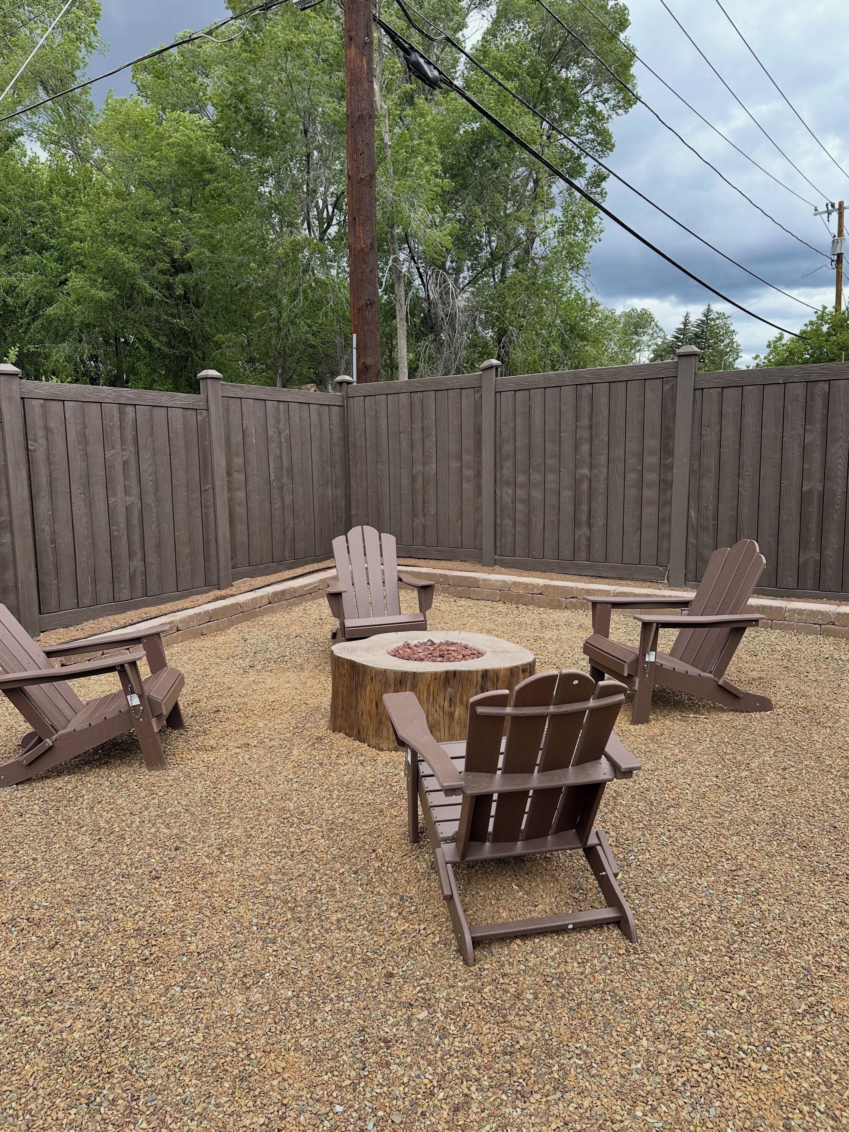 Un área de estar al aire libre con sillones Adirondack y un hogar circular.