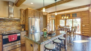 A spacious kitchen with a large island, wooden cabinets, and a stone backsplash. - Hike, Fish & More: Grand Cabin w/ Decks in Sturgis (Sturgis)