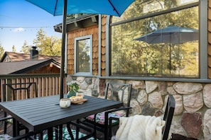 A patio with a table, chairs, and a blue umbrella.
