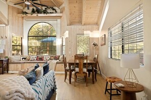 Um quarto aconchegante com uma janela grande, uma mesa de jantar e uma área de estar confortável.