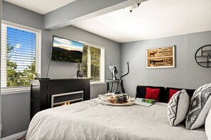 A bedroom with a bed, a TV, a fireplace, a treadmill, and a framed sign on the wall. - Casa Huntsted A-Frame Cabin near Snow Valley (Running Springs)