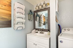 A bathroom with a sink, mirror, and stacked towels. - Casa Huntsted A-Frame Cabin near Snow Valley (Running Springs)