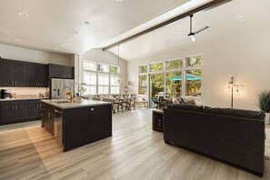 Una cocina amplia con armarios oscuros, una isla central y un comedor con un amplio ventanal.