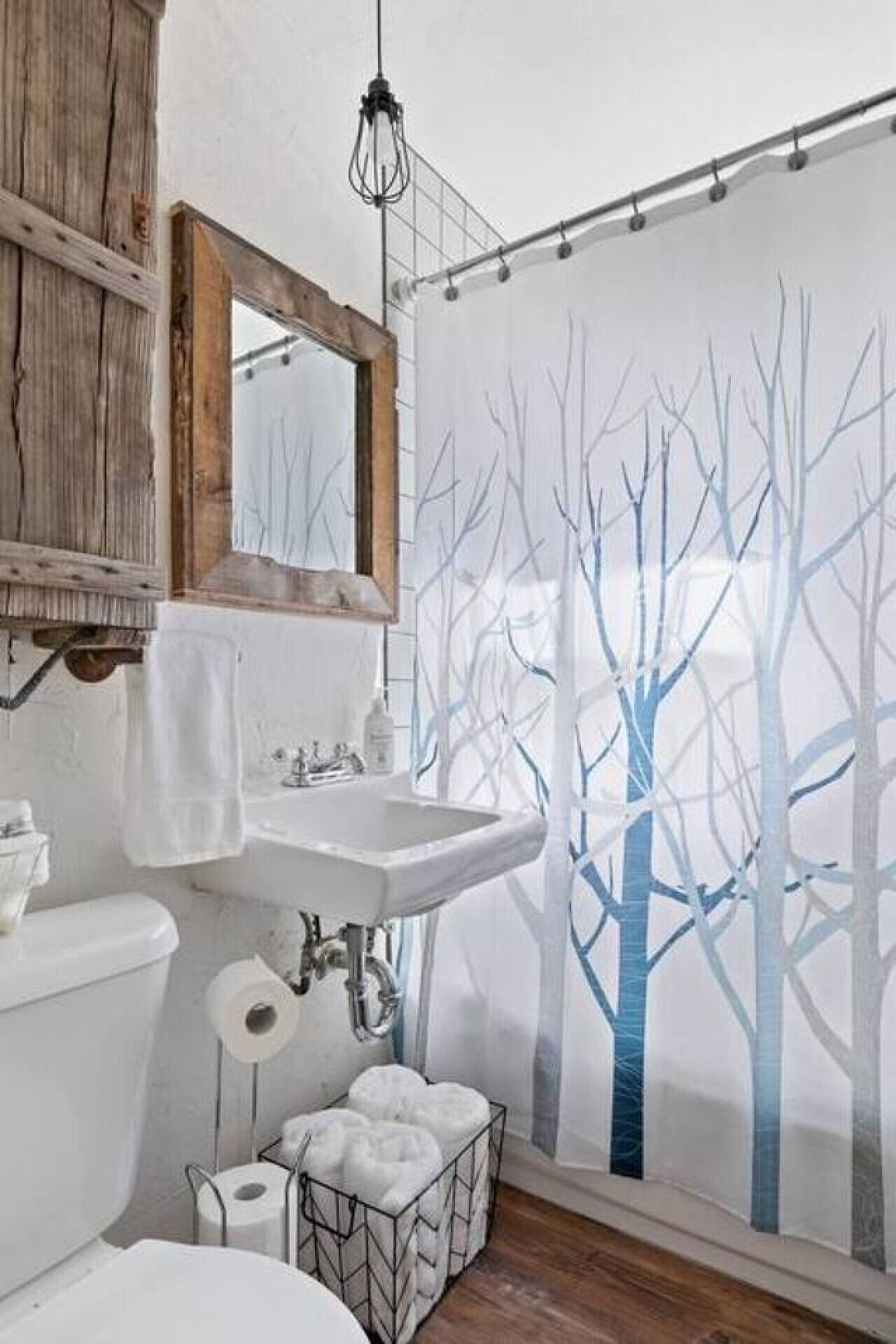 A bathroom with a wooden cabinet, a sink, a mirror, and a shower curtain with a tree design.