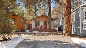 A cabin with a wooden deck and two red chairs outside. - Modern Chic Spruce Retreat - Hot Tub + AC + Pets (Big Bear)