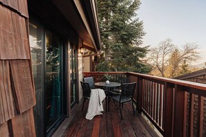A wooden deck with a round table and chairs, overlooking a forested area. - Summit Solace, Steps to Snow Summit w/ Hot tub (Big Bear Lake)