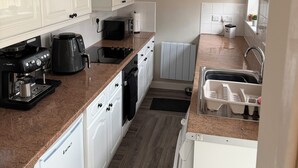 Eine kompakte Küche mit weißen Schränken, einer Kaffeemaschine, einem Toaster und einem Spülbecken.
