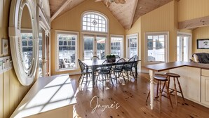 Un comedor espacioso con techo alto y ventanas amplias, un ventilador de techo de madera y vistas al exterior.