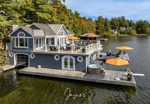 Una casa flotante grande con terraza, mobiliario exterior y un jacuzzi.