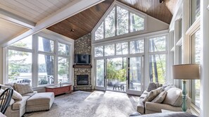 A spacious living room with a stone fireplace, large windows, and a cozy seating area. - 4 bed 4 bath cottage on Lake Rosseau (Port Carling)