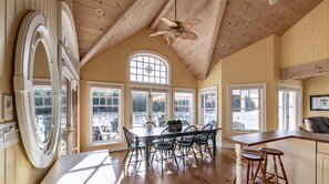 A spacious dining area with a high ceiling and large windows, a wooden ceiling fan, and a view of the outdoors. - 4 bed 4 bath cottage on Lake Rosseau (Port Carling)