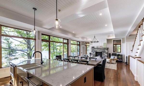 A modern kitchen with a large island, dining area, and a fireplace.