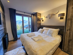 Quarto com uma cama grande, vista para montanhas e parede de madeira rústica.