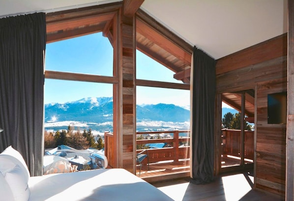Quarto com uma grande janela com vista para as montanhas.