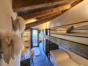 Une chambre rustique avec des lits superposés, un plafond en bois et un petit coin salon.