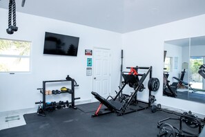 A gym with exercise equipment, a TV, and a door.