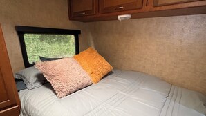 A bedroom with a bed, a window, and wooden cabinets.