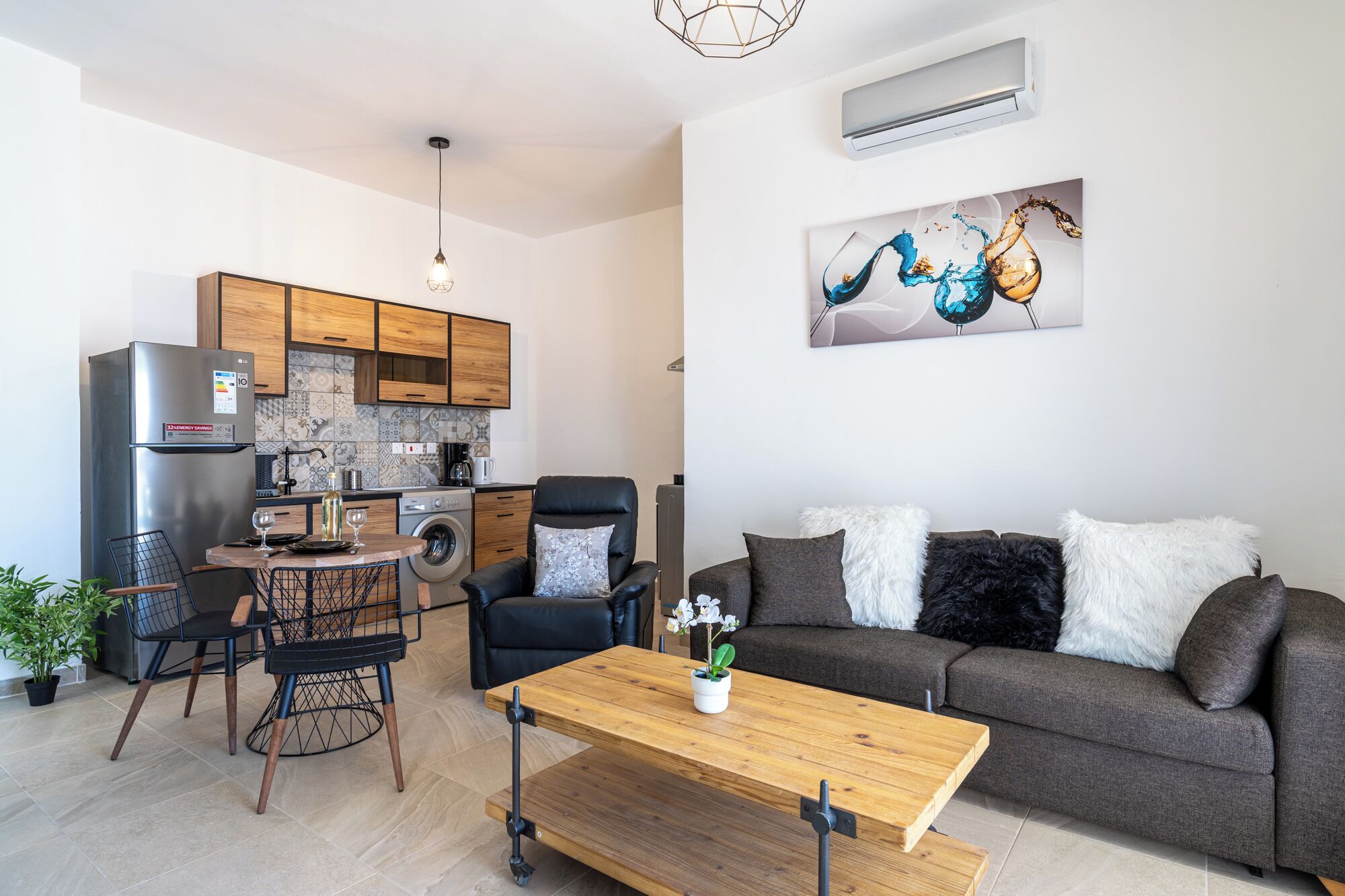 Ein moderner Wohnraum mit Küche, Essbereich und einer Couch mit dekorativen Kissen.