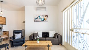 A modern living room with a sofa, coffee table, and a dining area. - Nala - 2 Bedroom Apt & Patio in Larnaca (Larnaca)
