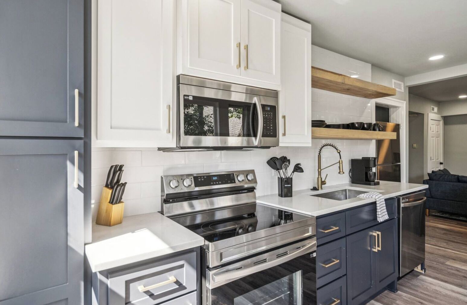 A modern kitchen with white cabinets, stainless steel appliances, and a wooden countertop.