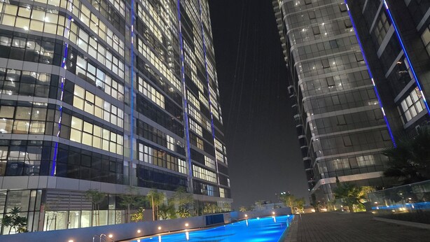 A nighttime view of a modern building with a swimming pool in the foreground.